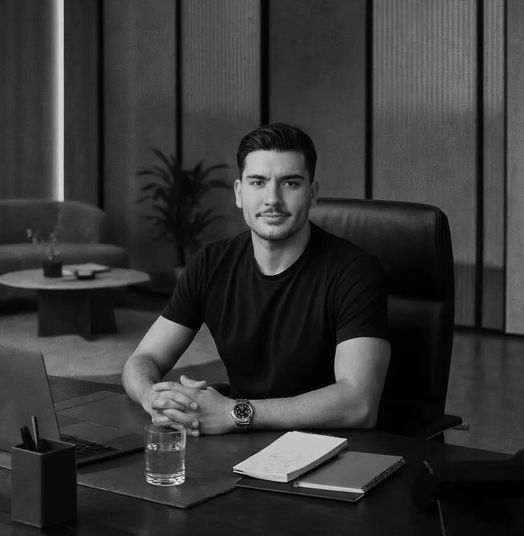 Pedro Screltz, diretor criativo e CMO do Grupo PV, sentado à mesa de trabalho, em preto e branco